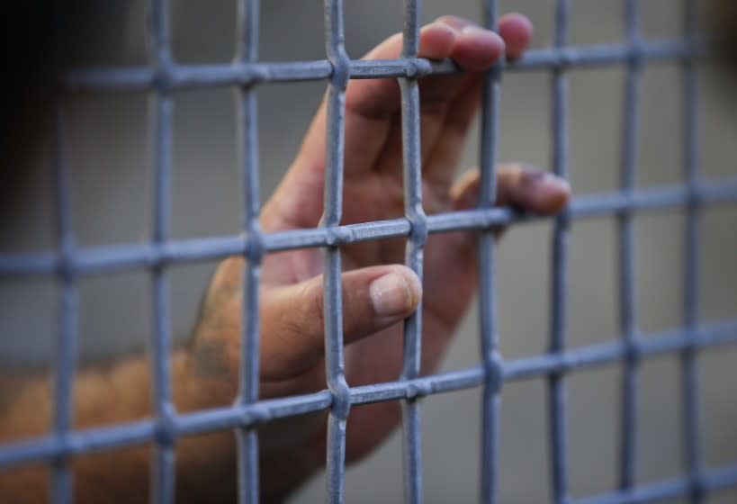 A condemned prisoner holds the mesh fence in the exercise yard during a media tour at San Quentin prison.