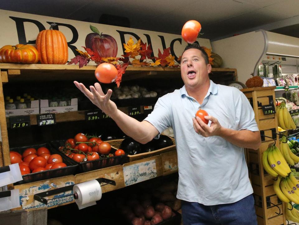 Tim Pastercyzk juggles some tomatoes inside Bradbury Brothers Market. He and wife, Michele Tourangeau, recently purchased the historic store in Cape Porpoise.
