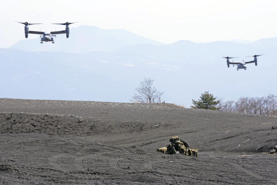 Two MV-22 Ospreys fly over as one of the members of the Japan Ground Self-Defense Force (JGSDF) guards a landing zone during a joint military drill between the JGSDF and the U.S. Marines at the Higashi Fuji range in Gotemba, southwest of Tokyo, Tuesday, March 15, 2022. (AP Photo/Eugene Hoshiko)