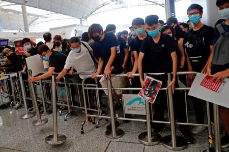 Anti-extradition bill protesters try to get close to the security gates during a mass demonstration after a woman was shot in the eye during a protest at Hong Kong International Airport, in Hong Kong