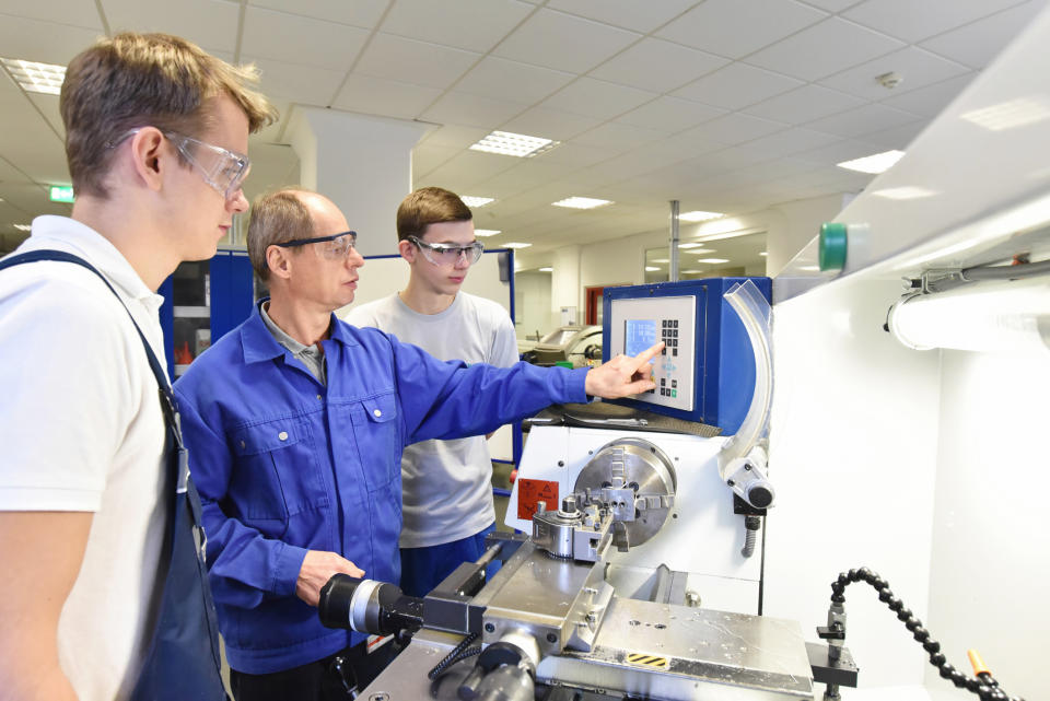 Young recruits being trained on a lathe.