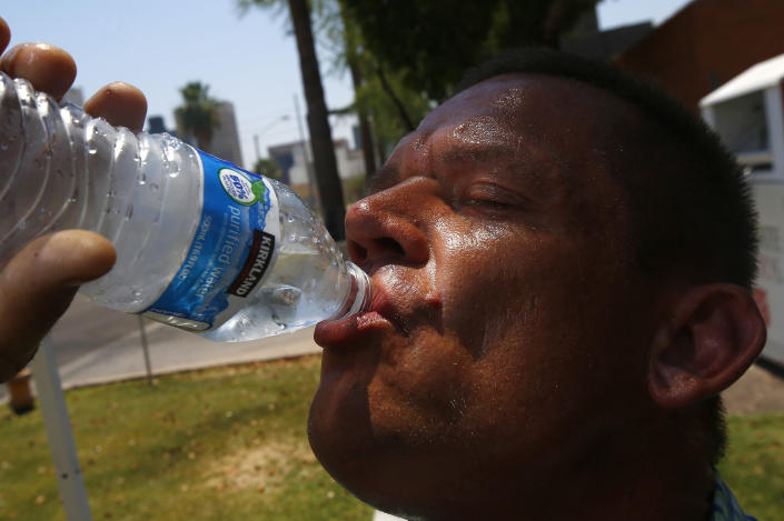 FILE - In this June 19, 2017 file photo Steve Smith takes a drink of water as he tries to keep hydrated and stay cool as temperatures climb to near-record highs, in Phoenix. As heat waves fueled by climate change arrive earlier, grow more intense and last longer, people over 60 who are more vulnerable to high temperatures are increasingly at risk of dying from heat-related causes. (AP Photo/Ross D. Franklin, File)