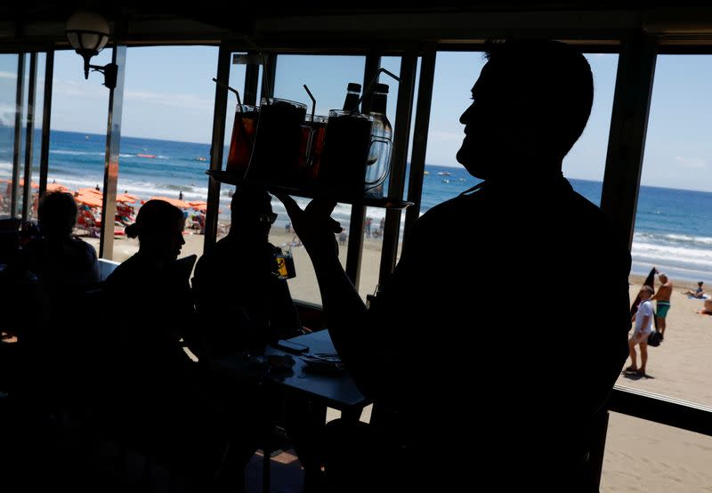 Un camarero sirve bebidas a los clientes en un restaurante en Playa del Inglés, Maspalomas en la isla de Gran Canaria