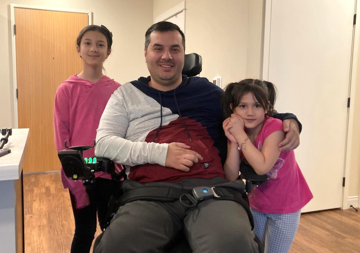 Arif Faizi, 34, poses for a photo with his two daughters, Salwa, 9, and Hafsa, 7, inside his apartment building in Milwaukee. Faizi, who was paralyzed in a car crash five years ago, fled Afghanistan with his family as the Taliban took over in 2021.