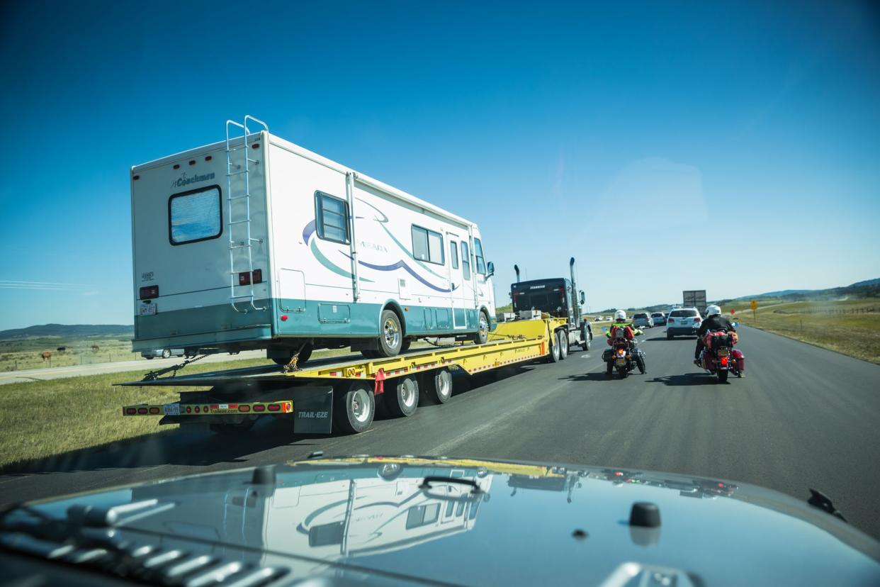 Edmonton, Canada - August 23, 2015: A broken down RV recreational vehicle being transported for repairs on a flat bed lorry trailer. View from a car on a main freeway route close to the city of Edmonton in Canada
