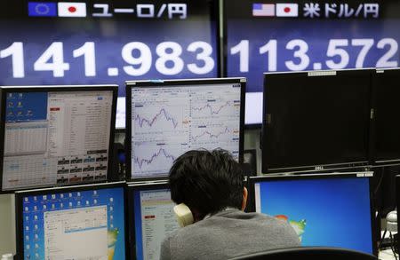 An employee of a foreign exchange trading company using a phone in front of monitors displaying the exchange rates between the Japanese yen and the U.S. dollar (R) and the yen against the euro (L) in Tokyo November 4, 2014. REUTERS/Yuya Shino