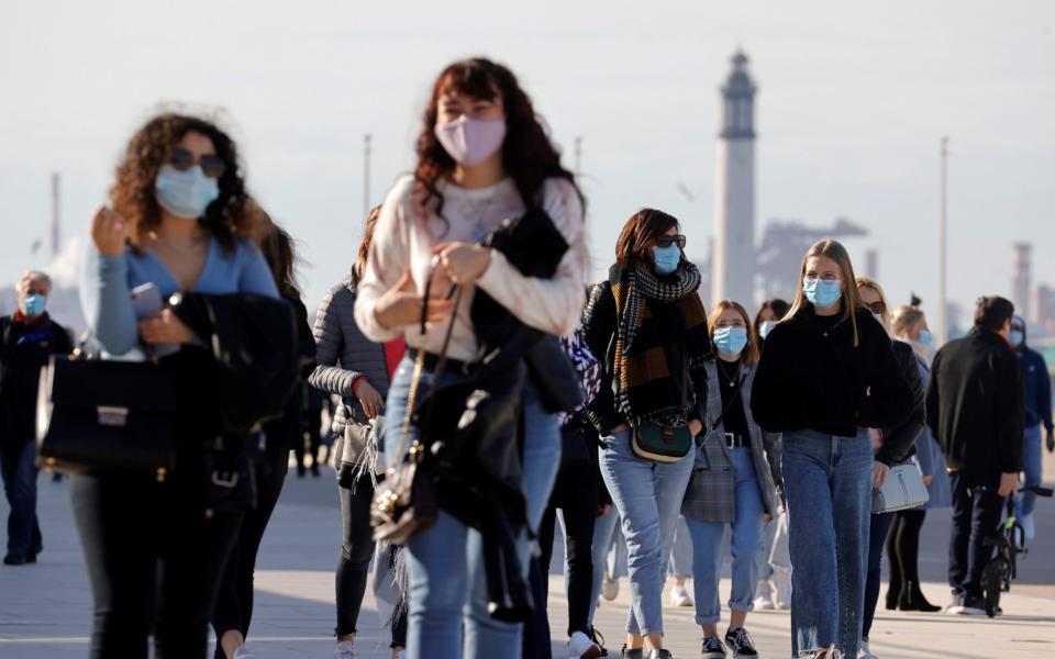 People wearing protective face masks walk near the beach in Dunkirk as the government eyes new measures to limit the spread of COVID-19 in the region, France - PASCAL ROSSIGNOL /REUTERS