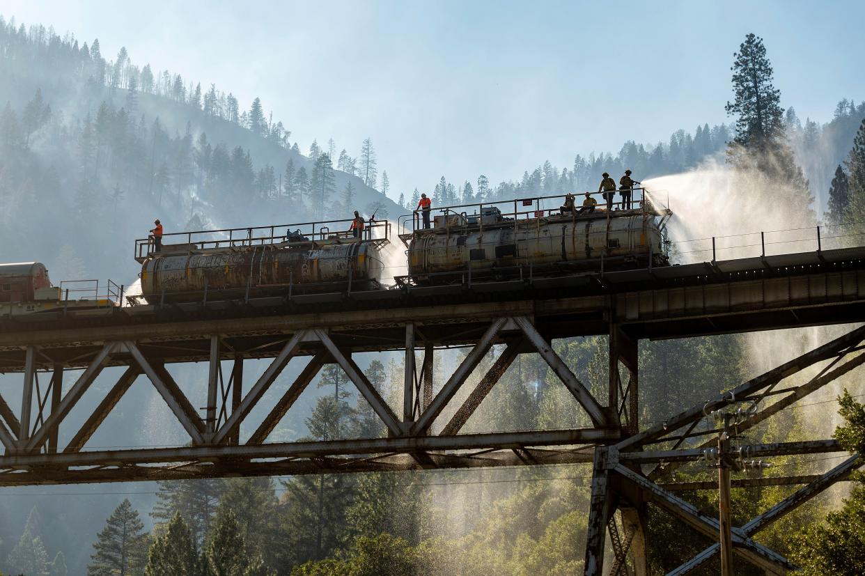 Firefighters spray water from Union Pacific Railroad's fire train while battling the Dixie Fire in Plumas National Forest, Calif. on Friday, July 16, 2021.