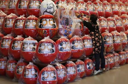 A staff adjusts the positions of Daruma dolls , which is believed to bring good luck, displayed at Daruma shop "Daimonya" in Takasaki, northwest of Tokyo November 23, 2014. REUTERS/Yuya Shino