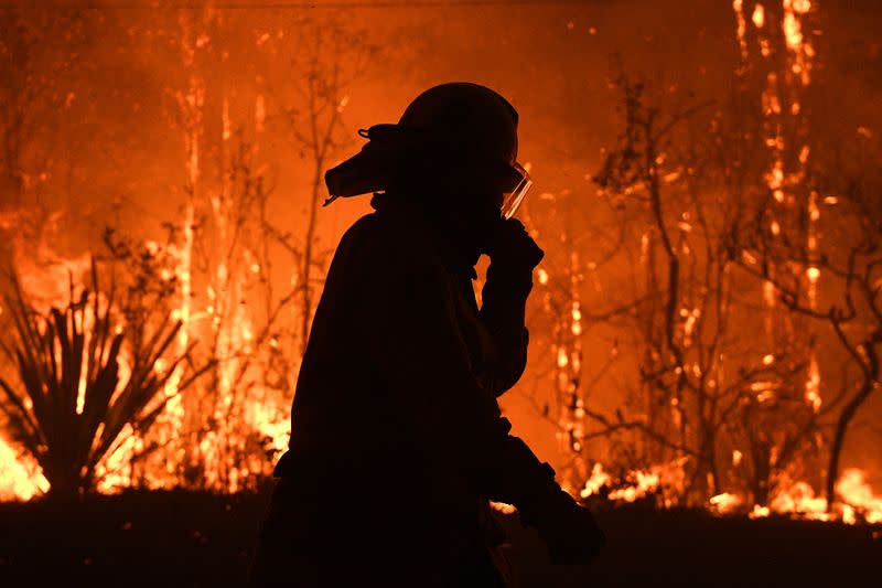 Los equipos del Servicio Rural de Bomberos de Nueva Gales del Sur protegen las propiedades de Waratah Road y Kelyknack Road cuando el incendio de Three Mile se aproxima a Mangrove Mountain, Australia