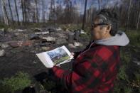 Julia Cardinal, right, shows a photo of what her cabin looked like before it was destroyed by wildfires, near Fort Chipewyan, Canada, on Sunday, Sep. 3, 2023. Cardinal lost the riverside cabin that was many things to her: retirement project, gift from from her husband, and somewhere to live by nature, as her family had done for generations. (AP Photo/Victor R. Caivano)