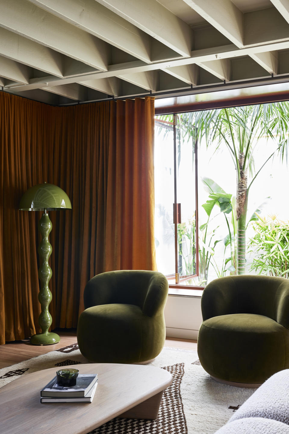 A living room with green decor including a floor lamp and glass bowl