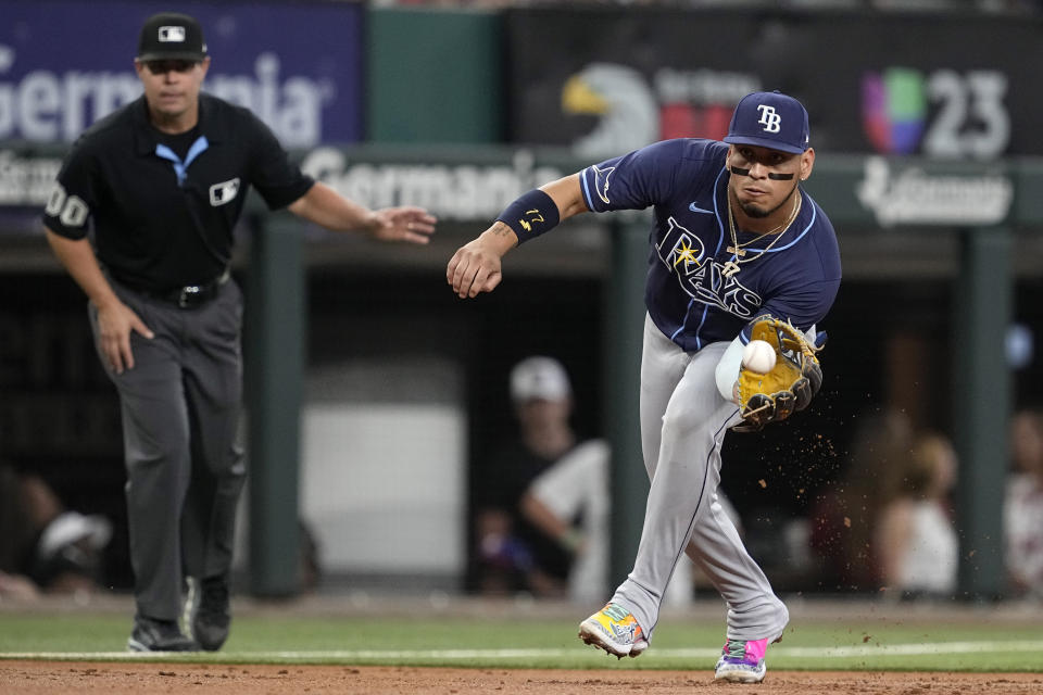 Tampa Bay Rays third baseman Isaac Paredes, right, reaches out to field a ground ball hit byTexas Rangers' Adolis Garcia in the second inning of a baseball game in Arlington, Texas, Saturday, July 6, 2024. Garcia was out at first on the play. (AP Photo/Tony Gutierrez)