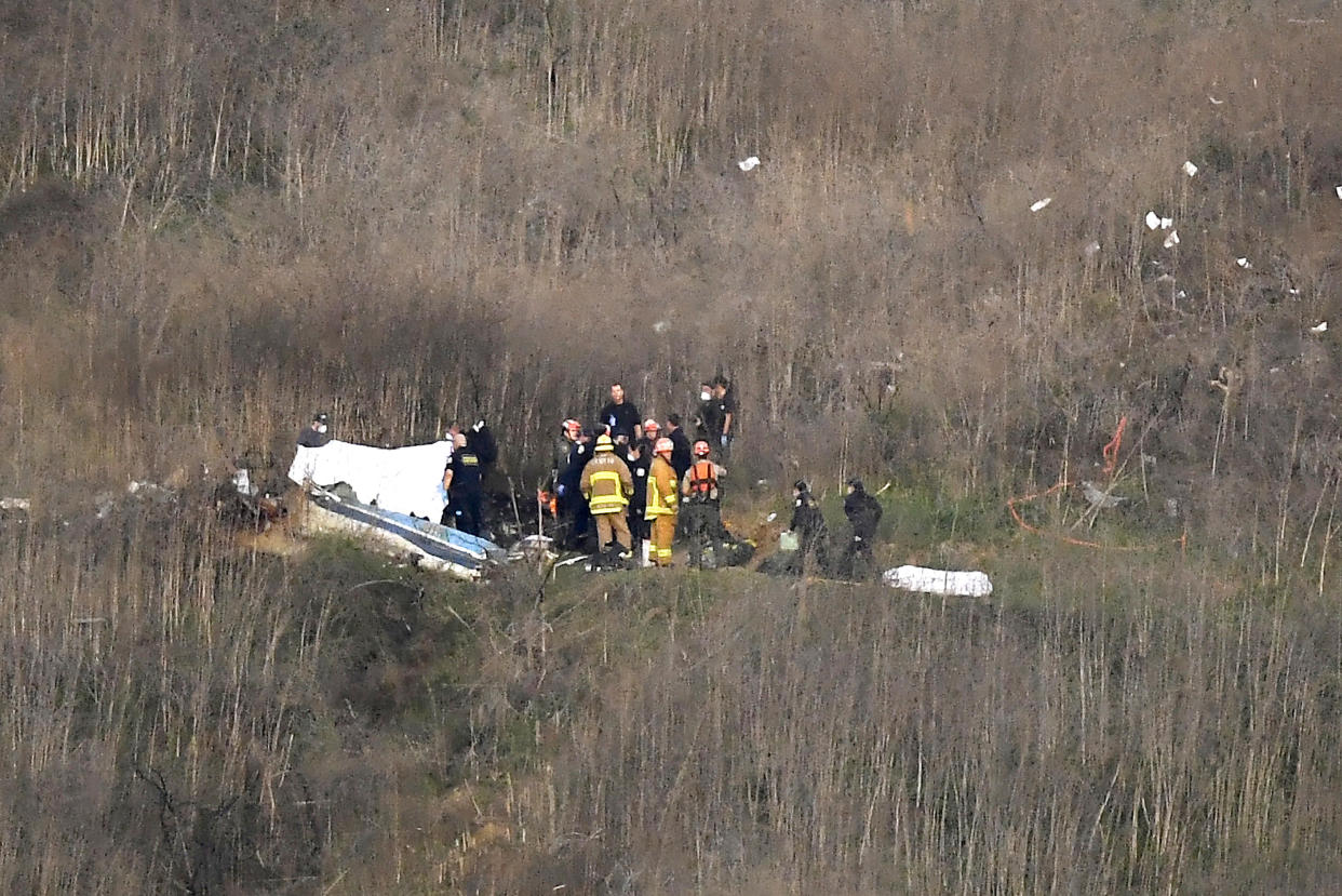 FILE - A body is covered, left, while another is seen at right at the scene of a helicopter crash that killed former NBA basketball player Kobe Bryant and eight others in Calabasas, Calif., Sunday, Jan. 26, 2020. Bryant's widow Vanessa Bryant on Tuesday, Sept. 22, 2020, filed a lawsuit against the Los Angeles County sheriff alleging negligence, invasion of privacy and intentional infliction of emotional distress after deputies allegedly shared unauthorized photos of the crash that killed her husband, their 13-year-old daughter and seven others. (AP Photo/Mark J. Terrill, File)