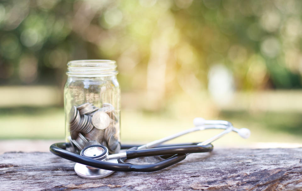 Coin and stethoscope on wooden background.