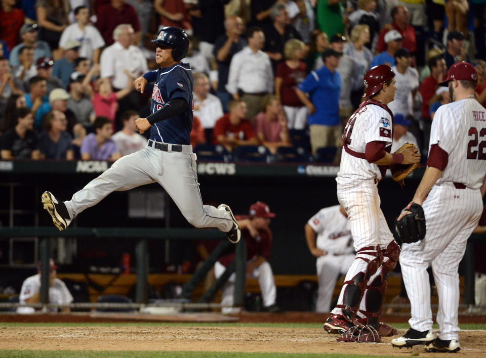 OMAHA, NE - JUNE 25: Robert Refsnyder #2 of the Arizona Wildcats celebrates his run for a 2-1 lead in front of Matt Price #22 and Grayson Greiner #21 of the South Carolina Gamecocks in the ninth inning during game 2 of the College World Series at TD Ameritrade Field on June 25, 2012 in Omaha, Nebraska. (Photo by Harry How/Getty Images)