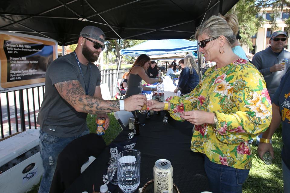 Ginnie Campbell, right, gets a sample of craft beer from Rick Willard of New Holland Brewing, left, during the Brick City Beer and Wine Festival at Citizens' Circle in Ocala back in 2019.