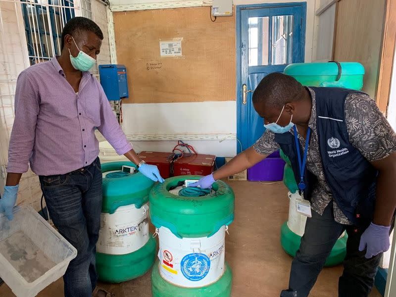 Workers from the World Health Organization (WHO) inspect an Arktek ultra-cold vaccine storage cylinder containing Ebola vaccines in Mbandaka