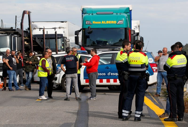 Spanish police officers and drivers stand on the motorway in Le Perthus near the Franco-Spanish border as Catalan demonstrators block the Spanish motorway during Catalonia's general strike