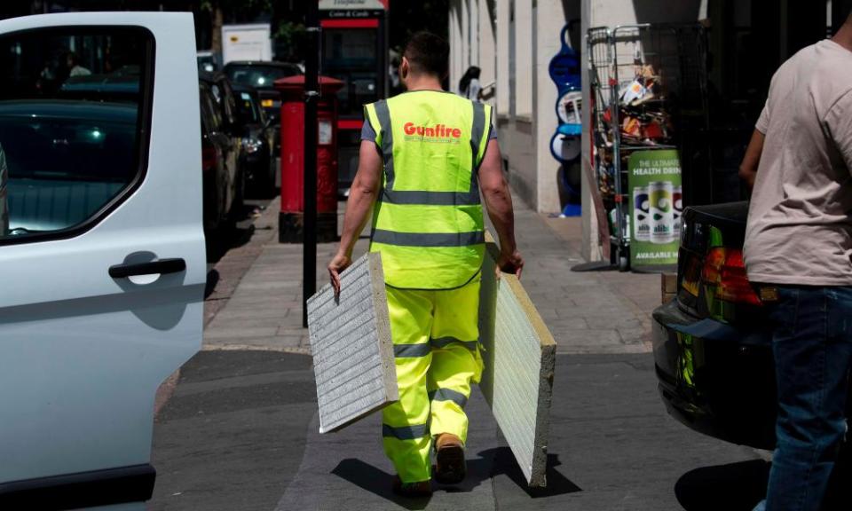 A worker carries cladding panels removed from a Camden tower block.