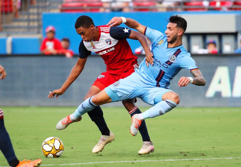 FC Dallas defender Reggie Cannon, left, holds off New York City midfielder Valentin Castellanos during the first half at Toyota Stadium in Frisco, Texas.