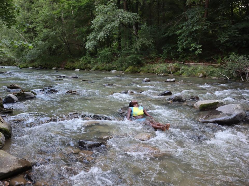 A woman lying back in a rocky river.