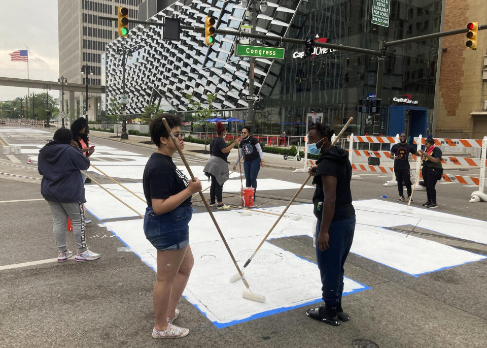 Students from University Prep Art Design celebrate Juneteenth by repainting a street mural, "Power To The People," in downtown Detroit on Saturday, June 19, 2021. (AP Photo/Ed White)