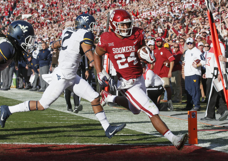 Oklahoma running back Rodney Anderson (24) scores in front of West Virginia safety Kenny Robinson (2) in the first quarter of an NCAA college football game in Norman, Oklahoma, Saturday, Nov. 25, 2017. (AP Photo/Sue Ogrocki)