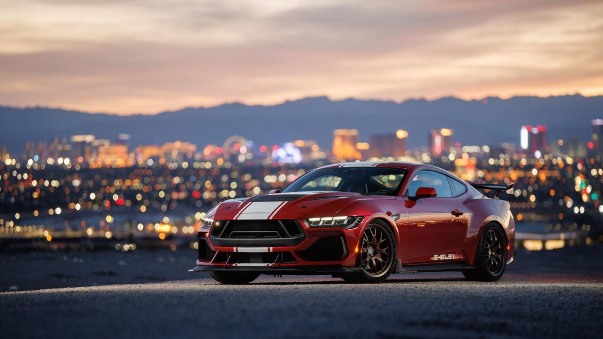 a red sports car on a road with a city in the background