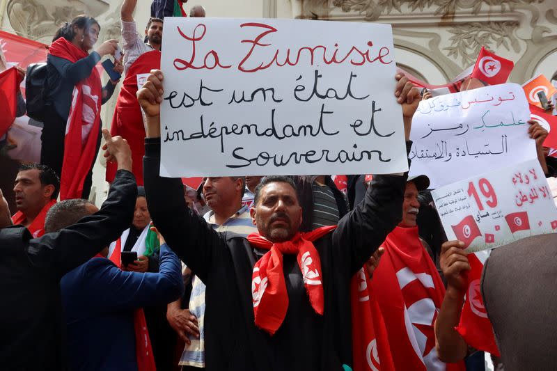 Supporters of Tunisian President Kais Saied carry flags and signs during a demonstration in Tunis
