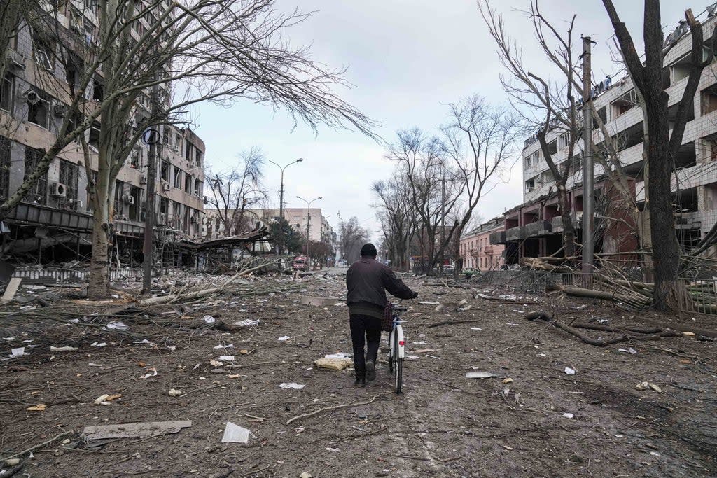 A man walks with a bicycle in a street damaged by shelling in Mariupol, Ukraine, on Thursday  (AP)