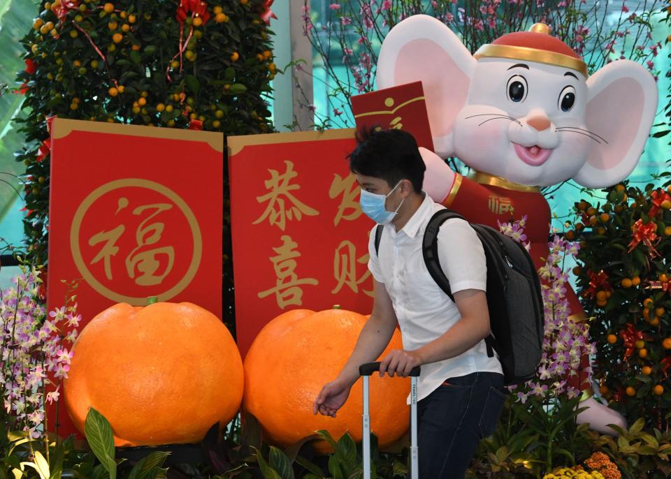 A traveller wearing a face mask walks past a Lunar New Year of the Rat display at Changi Airport on 30 January, 2020. (PHOTO: AFP via Getty Images)