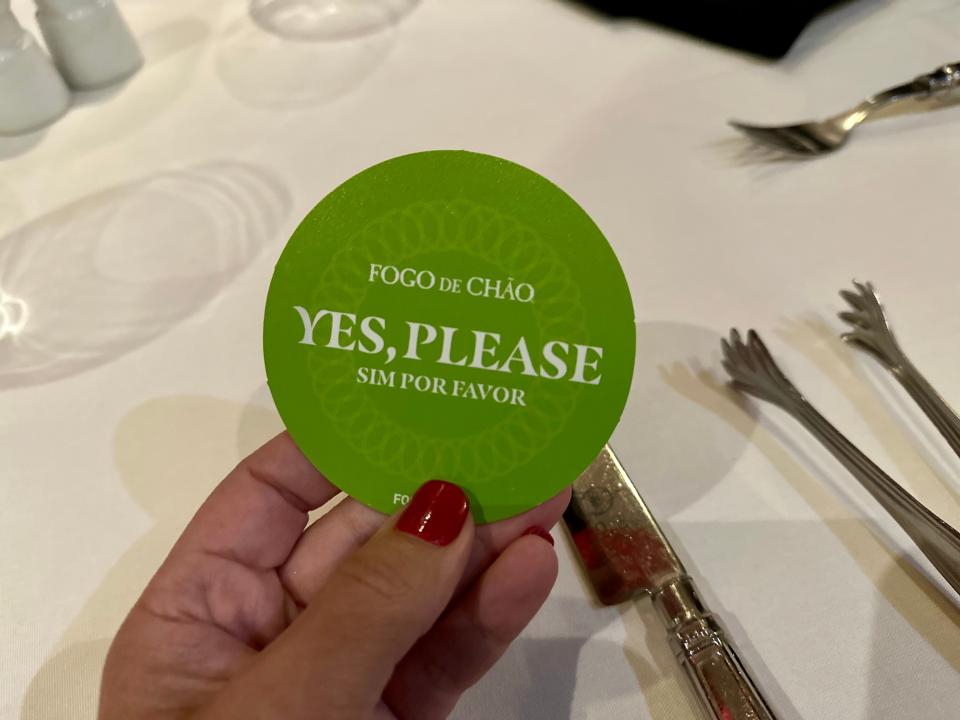 hand holding up a "yes" card at a table in fogo de chao