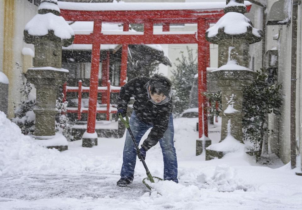 A person shovels the snow in front of a shrine Wednesday Jan. 25, 2023 in Tottori, Tottori Prefecture, western Japan. Snow and cold weather were affecting much of Japan on Wednesday, disrupting highway, air and train travel, and more snow and cold temperatures were forecast. (Kyodo News via AP)