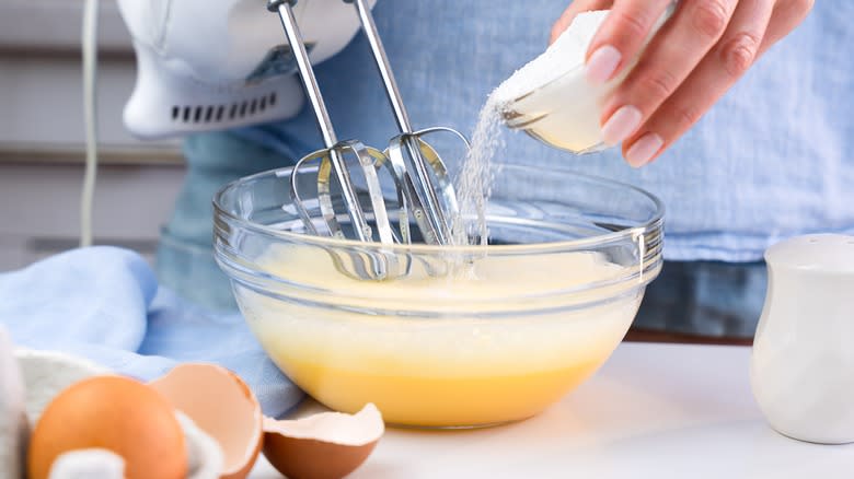 Adding sugar to eggs and whisking