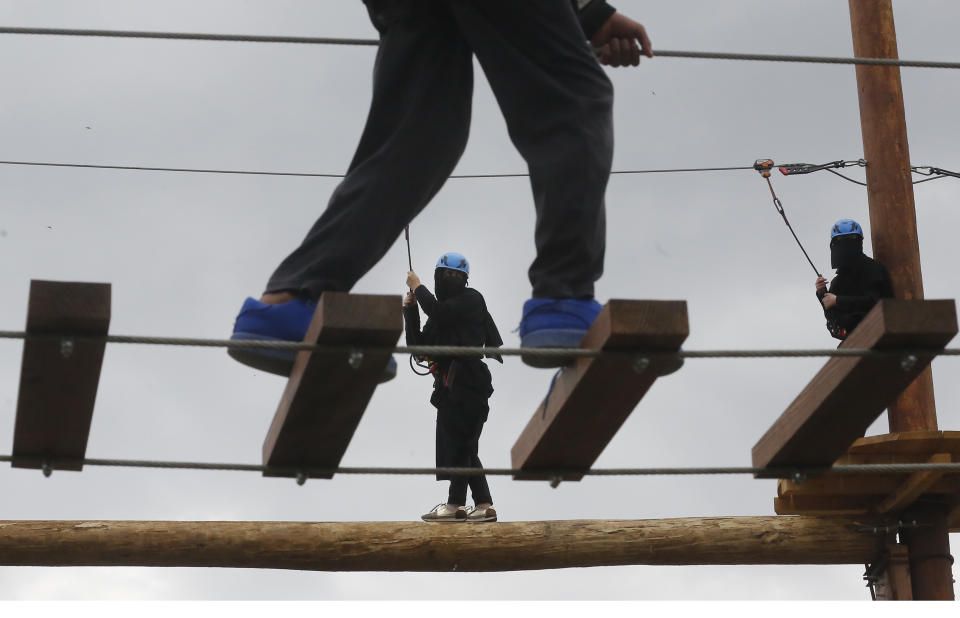 In this Saturday, Aug. 24, 2019 photo, Saudi women navigate an obstacle course during the al-Soudah festival in Abha, southwest Saudi Arabia. The al-Soudah festival, which ran throughout the month of August, gave visitors a chance to experience a unique region in Saudi Arabia and take part in outdoor sports like hiking, mountain cycling, paragliding, horseback riding, zip lining and bungee jumping. (AP Photo/Amr Nabil)