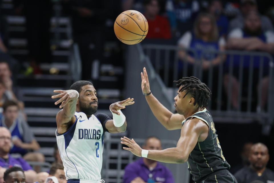 Dallas Mavericks guard Kyrie Irving (2) passes against Charlotte Hornets guard Dennis Smith Jr. during the first half of an NBA basketball game in Charlotte, N.C., Sunday, March 26, 2023. (AP Photo/Nell Redmond)