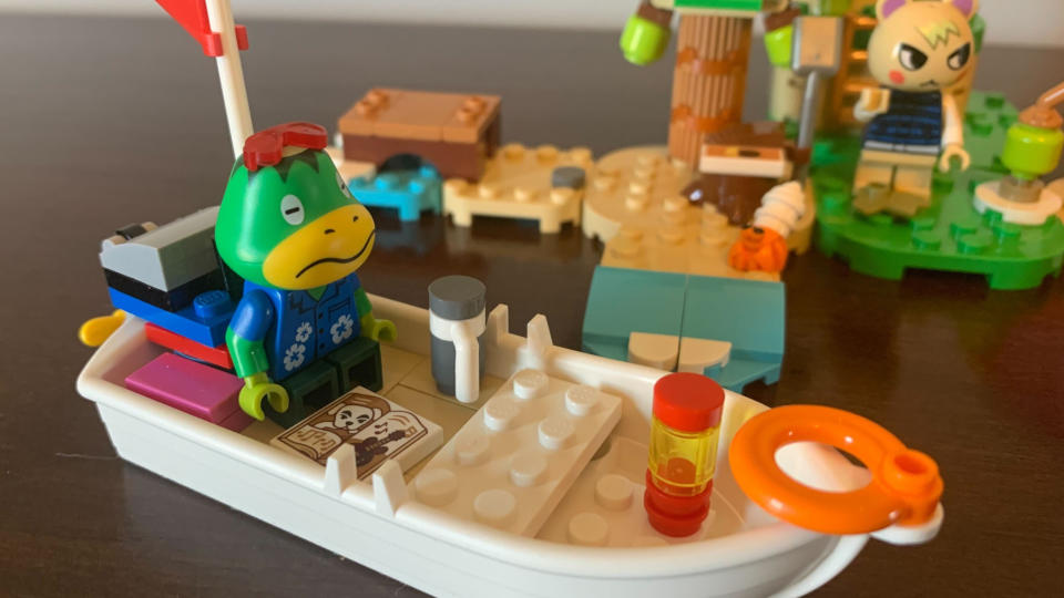 Lego Kapp'n's Island Boat Tour with a minifigure sitting in a boat, with a character seen on an island in the background