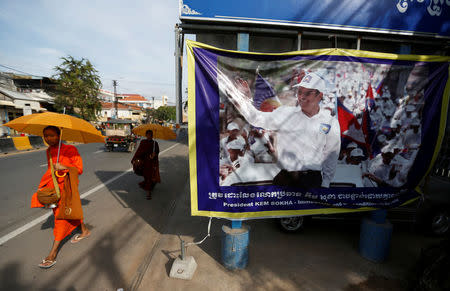 Buddhist monks walk past a banner of opposition leader and President of the Cambodia National Rescue Party (CNRP) Kem Sokha at the party's headquarters in Phnom Penh, Cambodia, November 17, 2017. REUTERS/Samrang Pring