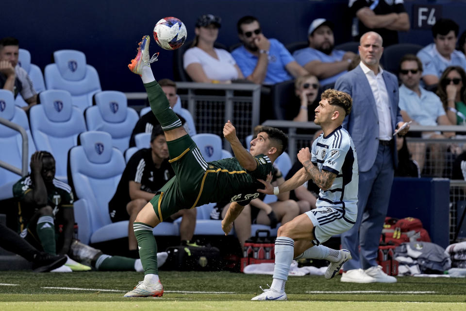 Portland Timbers defender Claudio Bravo, left, kicks the ball away from Sporting Kansas City midfielder Marinos Tzionis (77) during the second half of an MLS soccer match Sunday, May 28, 2023, in Kansas City, Kan. Sporting Kansas City won 4-1. (AP Photo/Charlie Riedel)