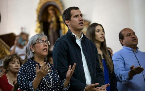 Opposition National Assembly President Juan Guaido, who declared himself interim president of Venezuela, prays next to his wife Fabiana Rosales - Credit: AP