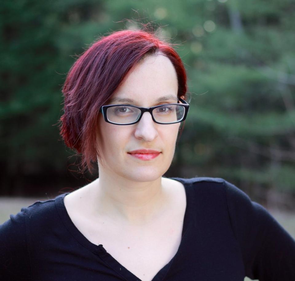 A woman with glasses and dark red hair.