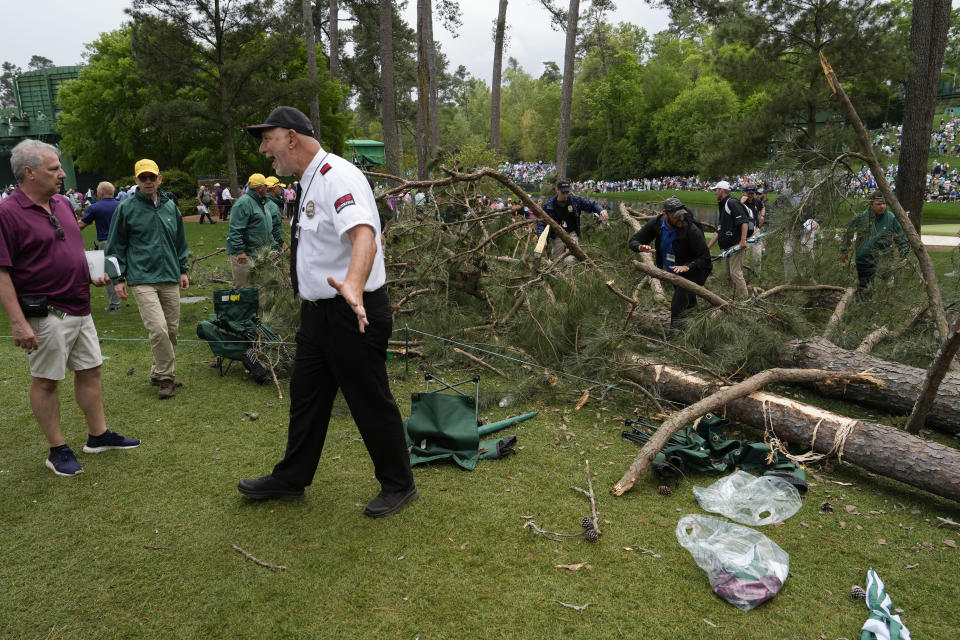 A security guard moves patrons away from trees that blew over on the 17th hole during the second round of the Masters golf tournament at Augusta National Golf Club on Friday, April 7, 2023, in Augusta, Ga. (AP Photo/Mark Baker)