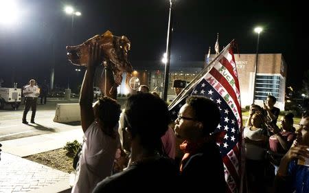 Protesters hold up a pig's head from a pig roast outside the police department in Ferguson, Missouri August 8, 2015. REUTERS/Rick Wilking