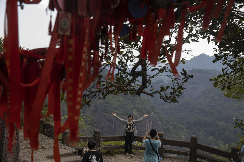 A visitor poses for a photo on Tianyou peak in Wuyishan in eastern China's Fujian province on Wednesday, Aug. 14, 2019. (AP Photo/Ng Han Guan)