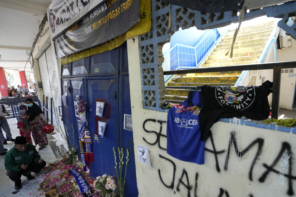 A man prays in front of gate 13 at Kanjuruhan Stadium where a soccer stampede killed more than 100 people on Saturday, in Malang, East Java, Indonesia, Tuesday, Oct. 4, 2022. Indonesian police said Tuesday that the gates at the soccer stadium where police fired tear gas and set off a deadly crush were too small and could only accommodate two at a time when hundreds were trying to escape. (AP Photo/Achmad Ibrahim)