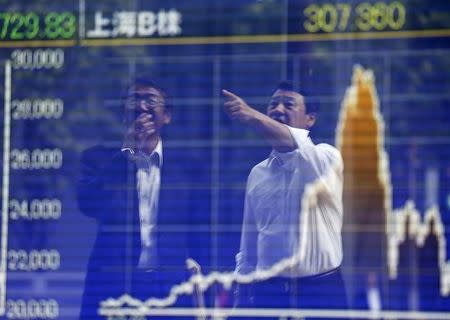 Tokyo businessmen react as they are reflected on a graph showing recent movements of Shanghai Stock Exchange B share index outside a brokerage in Tokyo, Japan, September 29, 2015. REUTERS/Issei Kato