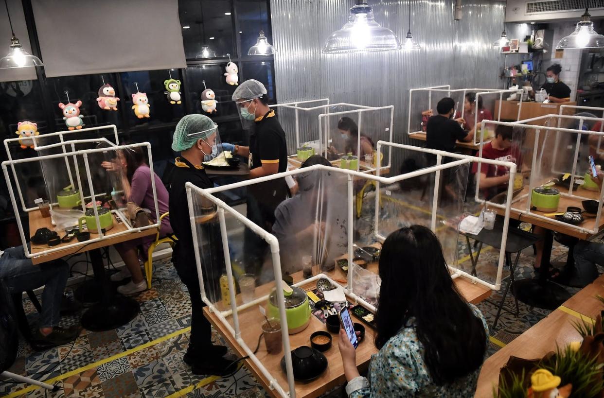 <span class="caption">A restaurant in Bangkok created plastic partitions and moved its tables farther apart to separate guests in a normally tight space.</span> <span class="attribution"><a class="link " href="http://gettyimages.com" rel="nofollow noopener" target="_blank" data-ylk="slk:Lillian Suwanrumpha/AFP/Getty Images;elm:context_link;itc:0;sec:content-canvas">Lillian Suwanrumpha/AFP/Getty Images</a></span>