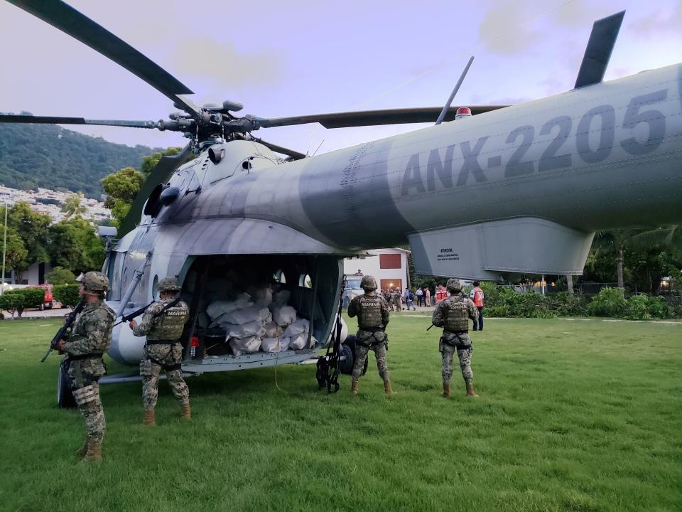 ADDS LOCATION - In this Thursday, Aug. 9, 2018 photo released by the Mexico's navy, soldiers stand guard around a military helicopter carrying packages of suspected cocaine, in Acapulco, Mexico. The Navy said in a statement Friday that it had seized nearly two tons of suspected cocaine off its southern Pacific coast. (Mexico Secretary of the Navy via AP)