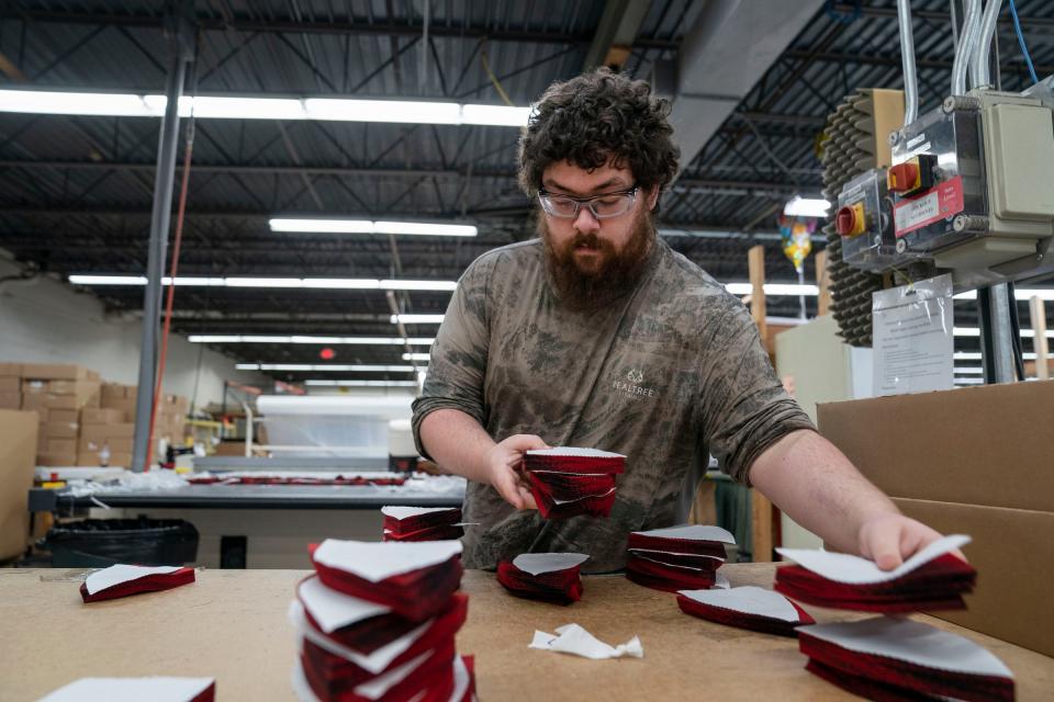 Mathew Harrison, 21, of Ironwood, separates cut fabric that will be used to make the Original, the red and black plaid Stormy Kromer hat, as he works in the Jacquart Fabric Products, home of Stormy Kromer, manufacturing facility in Ironwood on Thursday, Jan. 4, 2024.